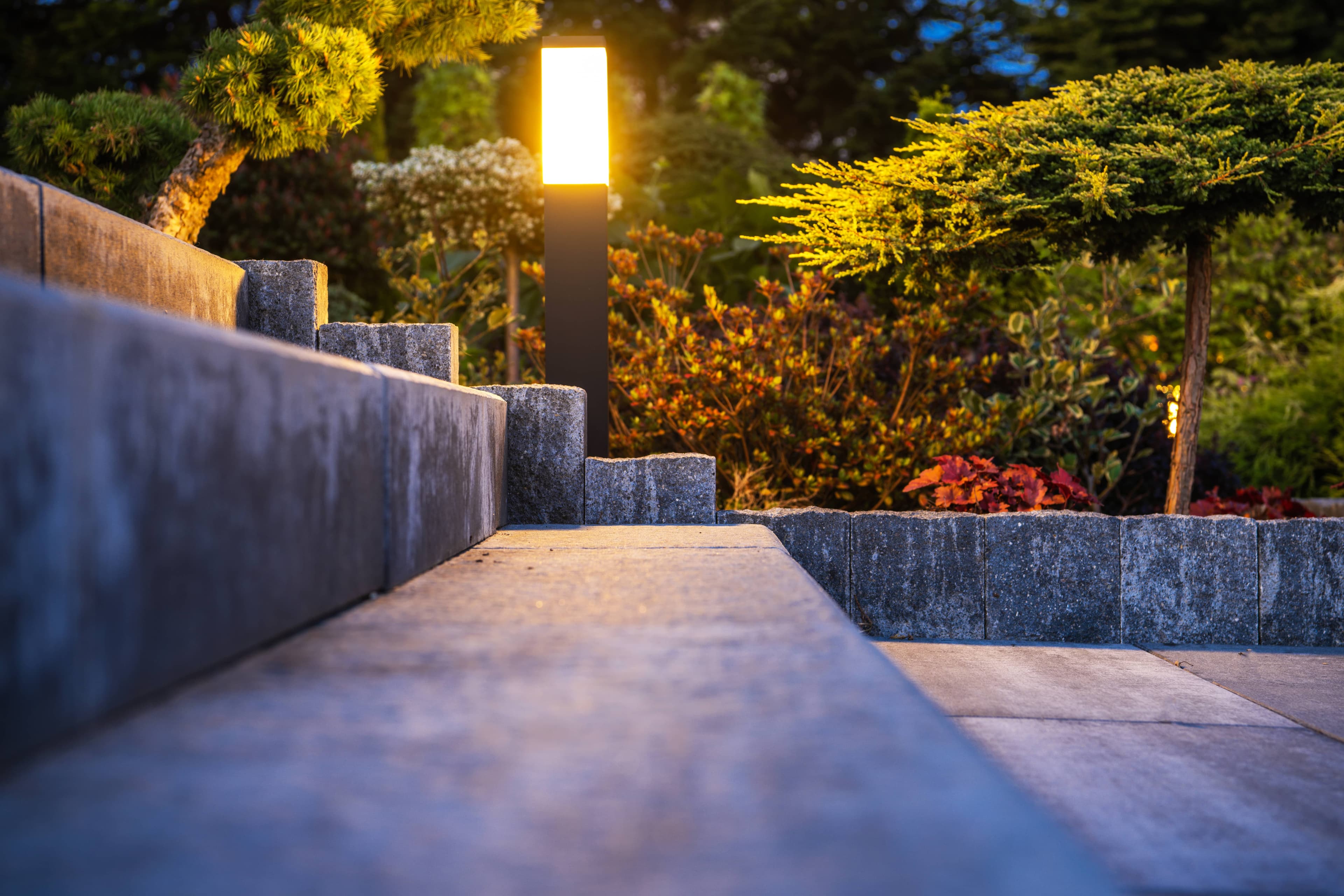 Modern pathway light illuminating a stone walkway and garden